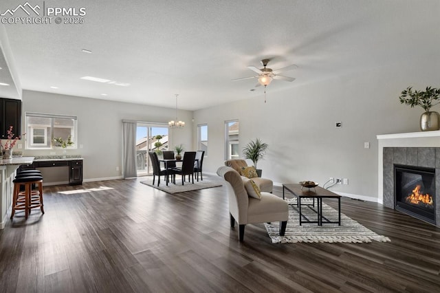 1632 Derbyshire St, Colorado Springs, CO 80910 - living room featuring ceiling fan with notable chandelier, baseboards, a textured ceiling, dark wood-style floors, and a tiled fireplace
