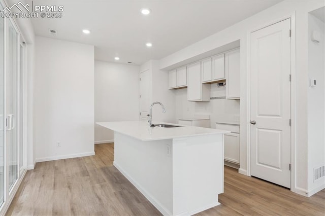 2489 Vanhoutte Vw, Colorado Springs, CO 80915 - kitchen featuring recessed lighting, a sink, a kitchen island with sink, light wood-style flooring, and white cabinetry