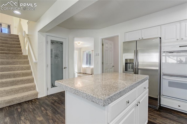 4730 Jenson Ln, Colorado Springs, CO 80922 - kitchen featuring white double oven, stainless steel fridge with ice dispenser, dark wood finished floors, white cabinetry, and light countertops