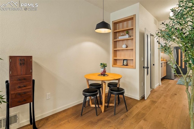 dining area featuring baseboards, visible vents, and light wood-style flooring