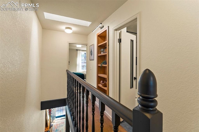 hallway featuring a textured wall and a skylight