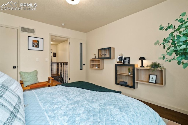 bedroom featuring visible vents, baseboards, and wood finished floors