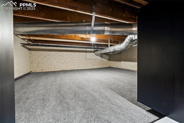 basement featuring carpet flooring and brick wall
