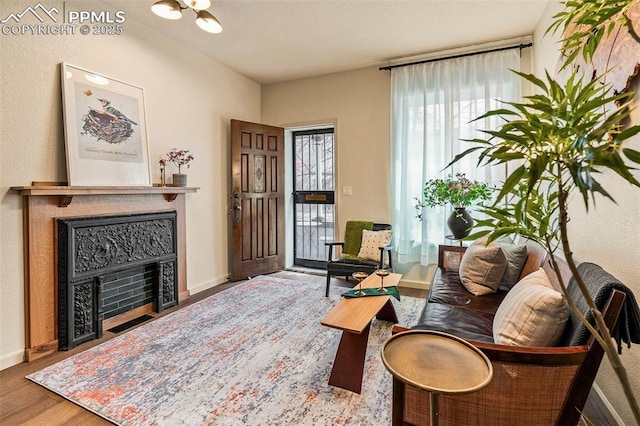 living room featuring baseboards, a fireplace with flush hearth, and wood finished floors