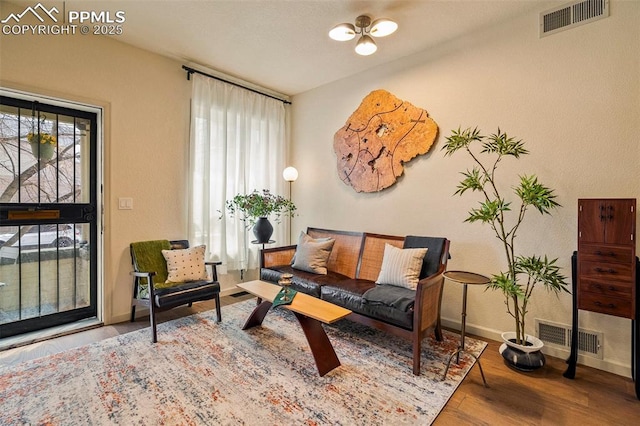 sitting room with baseboards, plenty of natural light, wood finished floors, and visible vents