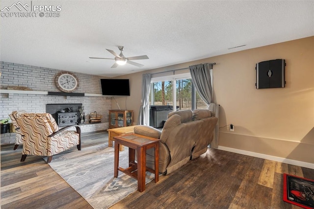 6770 Gun Club Trl, Colorado Springs, CO 80908 - living room featuring baseboards, ceiling fan, a wood stove, wood finished floors, and a textured ceiling