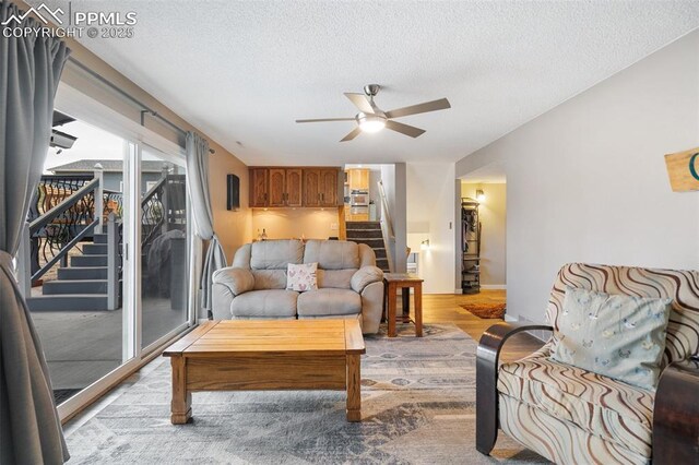 6770 Gun Club Trl, Colorado Springs, CO 80908 - living room with stairs, a ceiling fan, light wood-style floors, and a textured ceiling