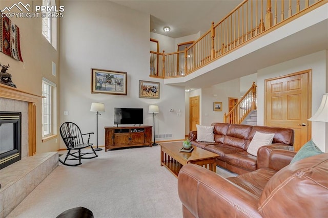 living room with stairs, a tile fireplace, a high ceiling, baseboards, and carpet