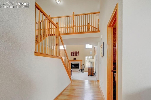hall featuring baseboards, stairs, a high ceiling, and wood finished floors