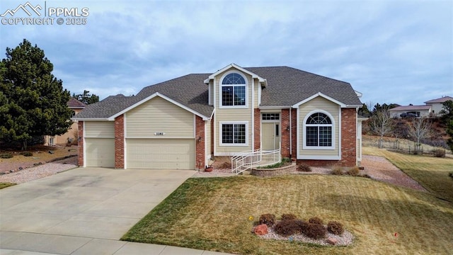 traditional-style home with driveway, a front yard, a garage, and brick siding