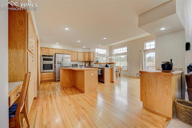 kitchen featuring light countertops, a kitchen island, light wood-style flooring, stainless steel appliances, and recessed lighting