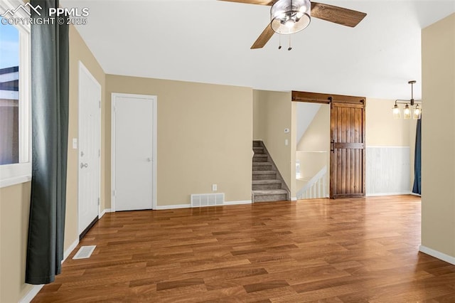 3781 Red Cedar Dr, Colorado Springs, CO 80906 - empty room with wood finished floors, ceiling fan with notable chandelier, a barn door, and visible vents