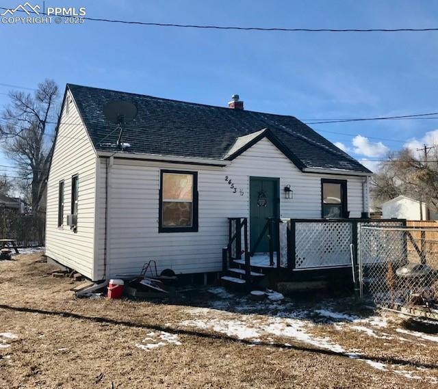 view of front of house featuring roof with shingles, a chimney, and fence