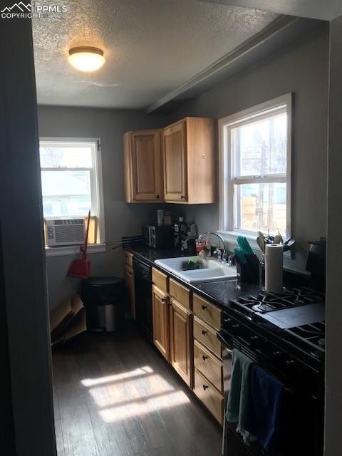 kitchen featuring dark countertops, cooling unit, wood finished floors, black appliances, and a sink