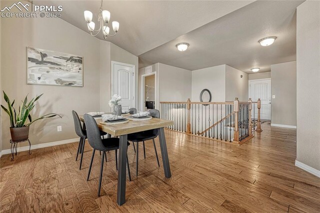 9812 Fairway Glen Dr, Peyton, CO 80831 - dining space with wood finished floors, lofted ceiling, baseboards, visible vents, and an inviting chandelier