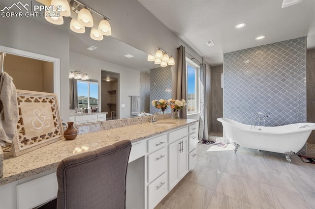 10790 Rolling Peaks Dr, Peyton, CO 80831 - full bath featuring tiled shower, vanity, a soaking tub, visible vents, and tile walls