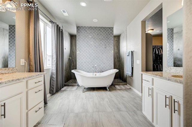 10790 Rolling Peaks Dr, Peyton, CO 80831 - bathroom featuring tile walls, visible vents, a freestanding tub, and two vanities