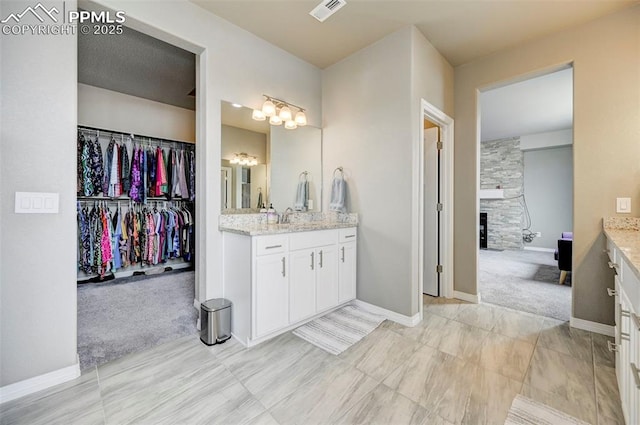 10790 Rolling Peaks Dr, Peyton, CO 80831 - bathroom featuring visible vents, a notable chandelier, vanity, and a fireplace