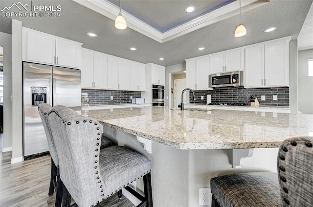 10790 Rolling Peaks Dr, Peyton, CO 80831 - kitchen featuring crown molding, a raised ceiling, a sink, white cabinets, and appliances with stainless steel finishes