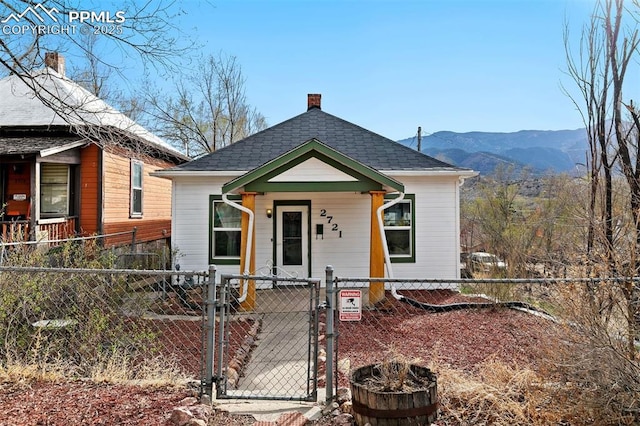2721 W Bijou St, Colorado Springs, CO 80904 - shotgun-style home featuring a gate, a fenced front yard, a chimney, and a mountain view
