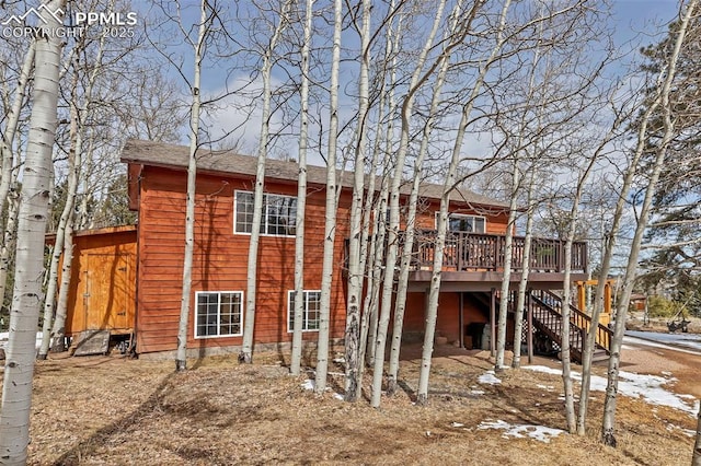 rear view of property featuring a carport, stairs, and a deck