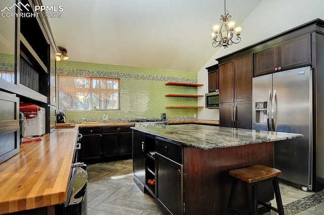 5581 County Road 328, Westcliffe, CO 81252 - kitchen featuring light stone counters, an inviting chandelier, open shelves, stainless steel appliances, and vaulted ceiling