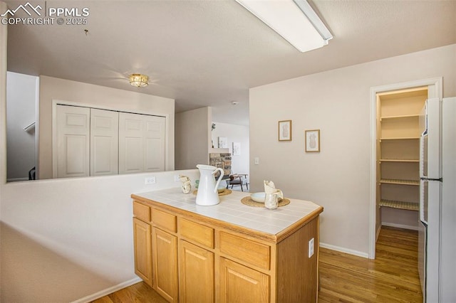 3272 Capstan Way, Colorado Springs, CO 80906 - kitchen featuring baseboards, tile counters, light wood-type flooring, and freestanding refrigerator