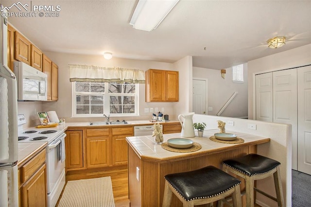 3272 Capstan Way, Colorado Springs, CO 80906 - kitchen featuring tile counters, white appliances, a breakfast bar, a kitchen island, and a sink