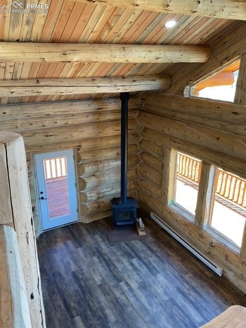 1906 Korlkoff Ln, Fort Garland, CO 81133 - unfurnished living room with beam ceiling, a wood stove, dark wood-style flooring, wooden ceiling, and baseboard heating
