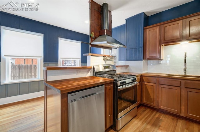 3010 W Kiowa St, Colorado Springs, CO 80904 - kitchen featuring butcher block countertops, a sink, light wood-style flooring, appliances with stainless steel finishes, and wall chimney exhaust hood