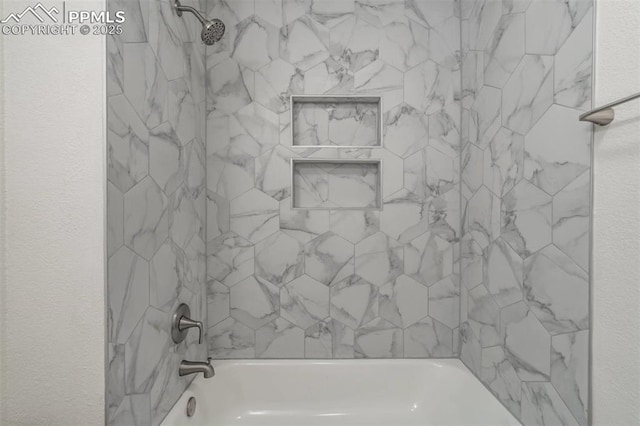 bathroom featuring a textured wall and bathtub / shower combination