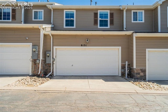 view of property featuring stone siding, concrete driveway, and an attached garage