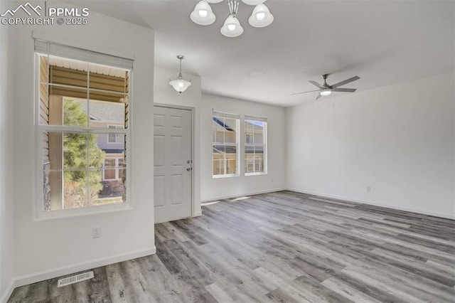 foyer entrance with a wealth of natural light, visible vents, wood finished floors, and ceiling fan with notable chandelier