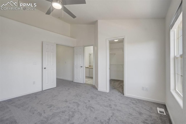 unfurnished bedroom with visible vents, baseboards, ensuite bath, carpet floors, and a walk in closet