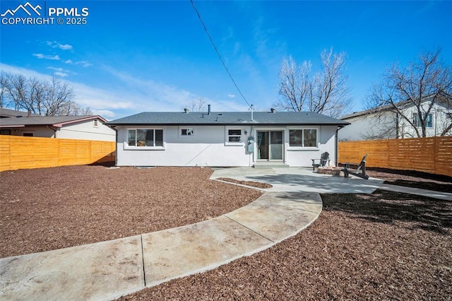 rear view of property with a fenced backyard, an outdoor fire pit, stucco siding, and a patio area