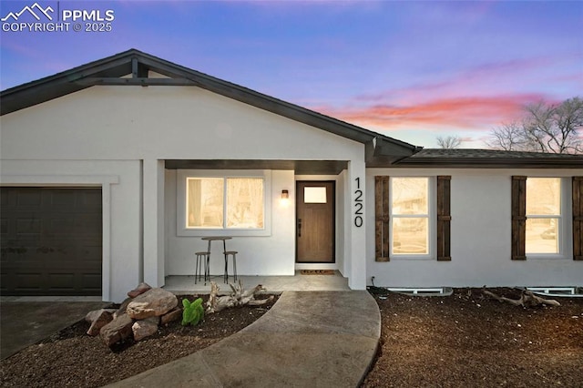 view of front facade featuring stucco siding, a porch, and an attached garage