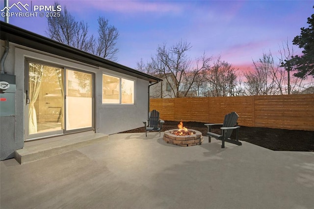 patio terrace at dusk with a fire pit and fence