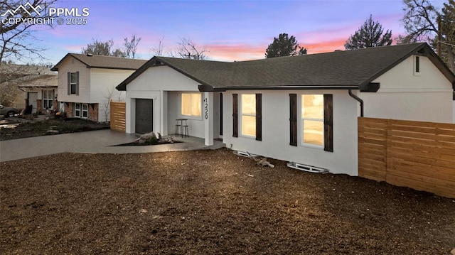 view of front of property with fence, driveway, stucco siding, and a garage