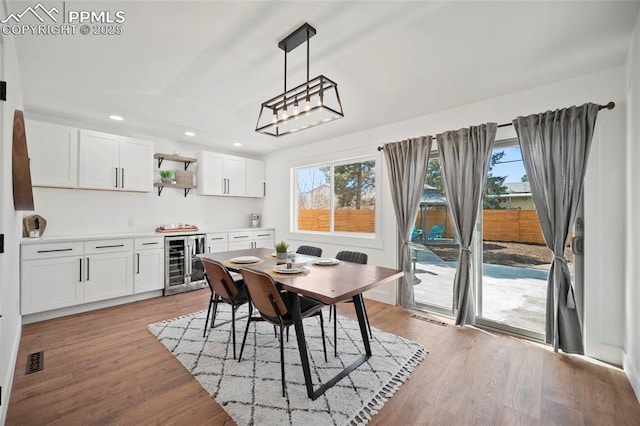 dining room with visible vents, light wood-style flooring, recessed lighting, lofted ceiling, and beverage cooler