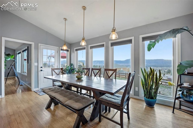 dining area featuring vaulted ceiling, light wood finished floors, baseboards, and a mountain view