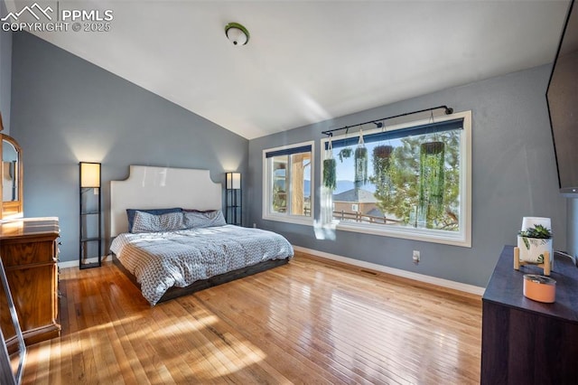 bedroom featuring lofted ceiling, hardwood / wood-style flooring, and baseboards