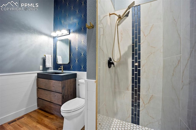 full bath featuring wood finished floors, toilet, a tile shower, and vanity