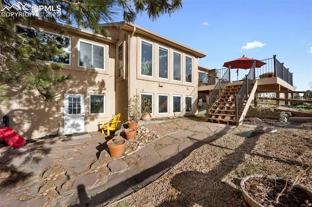 rear view of property with stairs, stucco siding, and a wooden deck