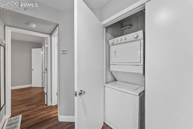 laundry room with stacked washer / dryer, baseboards, and dark wood-type flooring