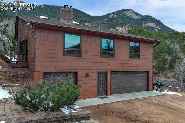5865 Waterfall Loop, Manitou Springs, CO 80829 - view of front facade with dirt driveway, a garage, a mountain view, and a chimney