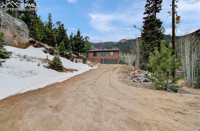 5865 Waterfall Loop, Manitou Springs, CO 80829 - view of front of house with driveway, an attached garage, and a chimney