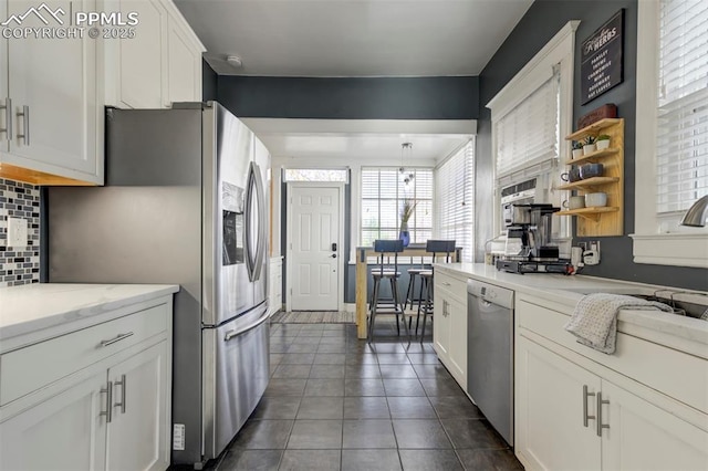 kitchen with tasteful backsplash, open shelves, white cabinets, appliances with stainless steel finishes, and dark tile patterned floors