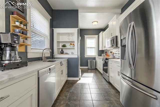 kitchen featuring a sink, stainless steel appliances, open shelves, tasteful backsplash, and white cabinets