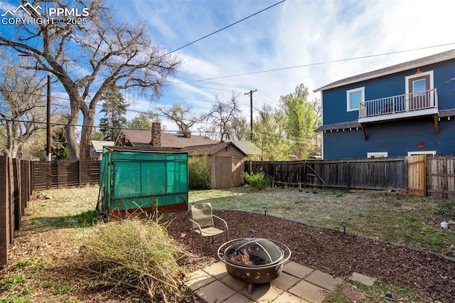 view of yard featuring an outbuilding, a shed, a fire pit, and a fenced backyard