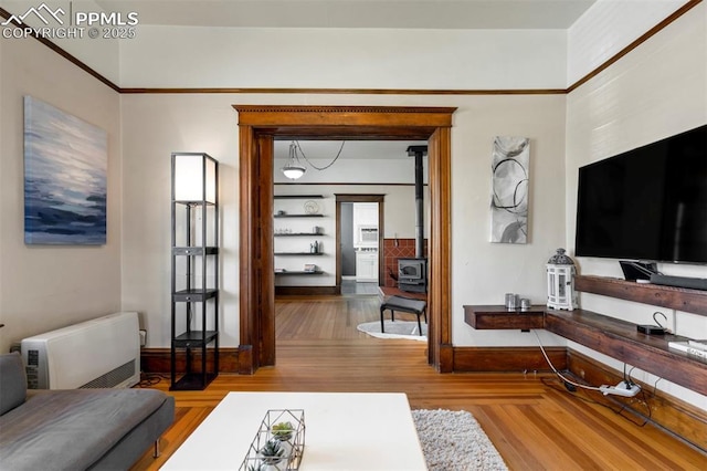 living room with wood finished floors, heating unit, a wood stove, and baseboards